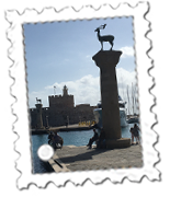 Two deer guard the entrance to Mandraki Port with the Lighthouse of Agios Nikolaus in the background